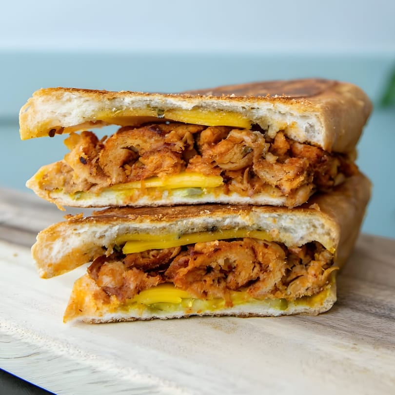 A Cubano's ATL sandwich, sliced in half, revealing shredded pork, cheese, and pickles.